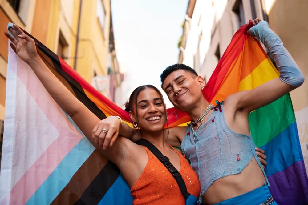 Duas pessoas felizes e orgulhosas, segurando a bandeira do orgulho LGBTQIAPN+